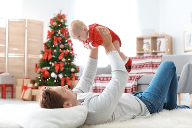 Photo of Young man with baby in Christmas suit at home
