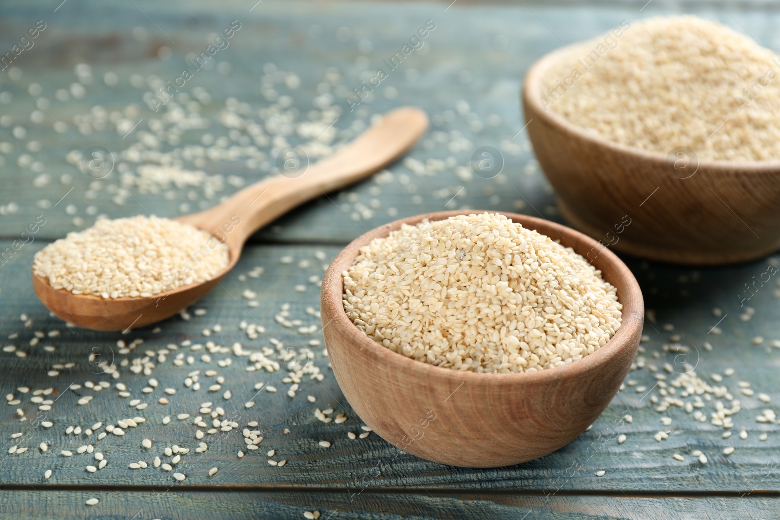 Photo of White sesame seeds on light blue wooden table