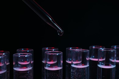 Photo of Dripping reagent into test tube on black background, closeup. Laboratory analysis