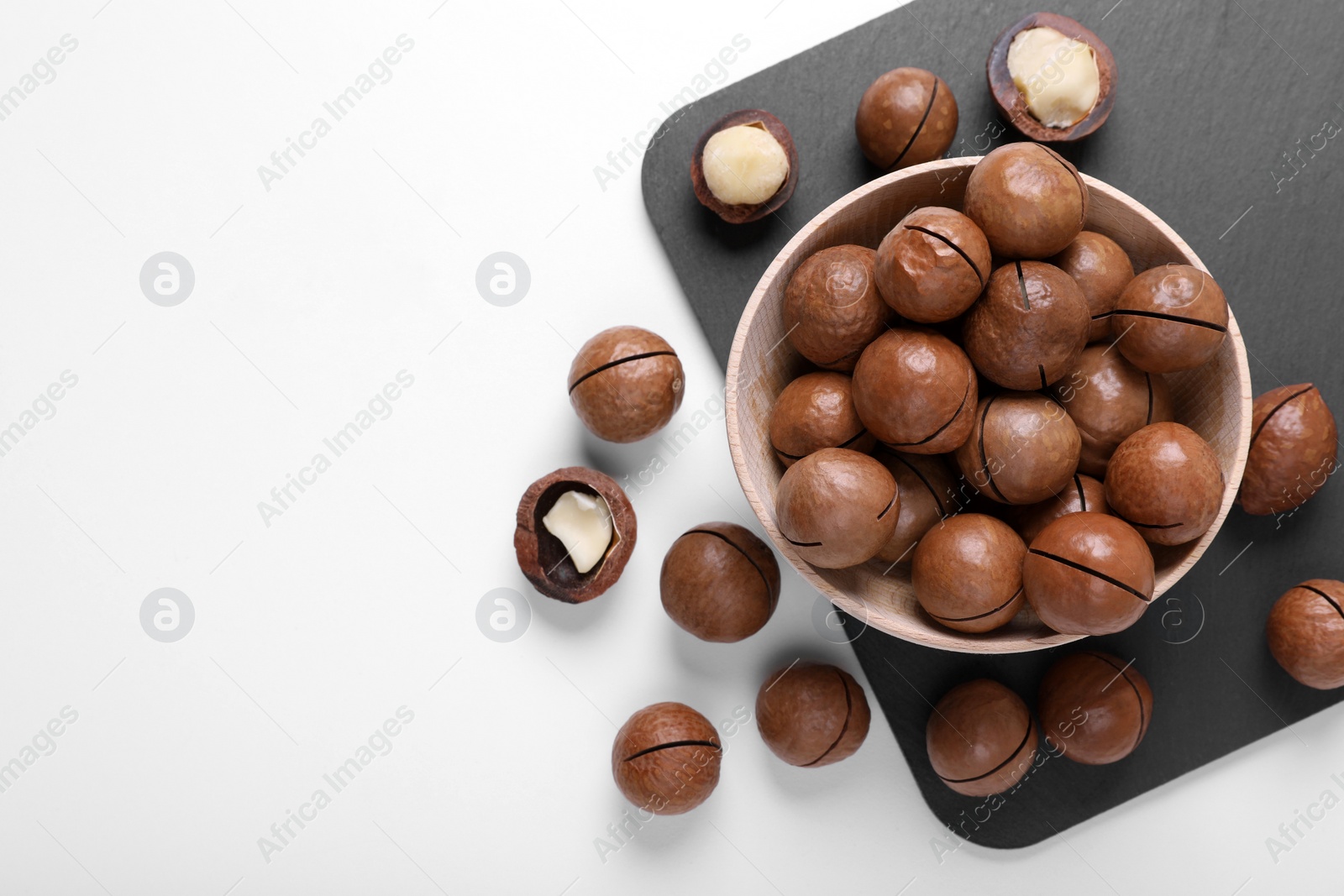Photo of Delicious organic Macadamia nuts on white background, flat lay. Space for text