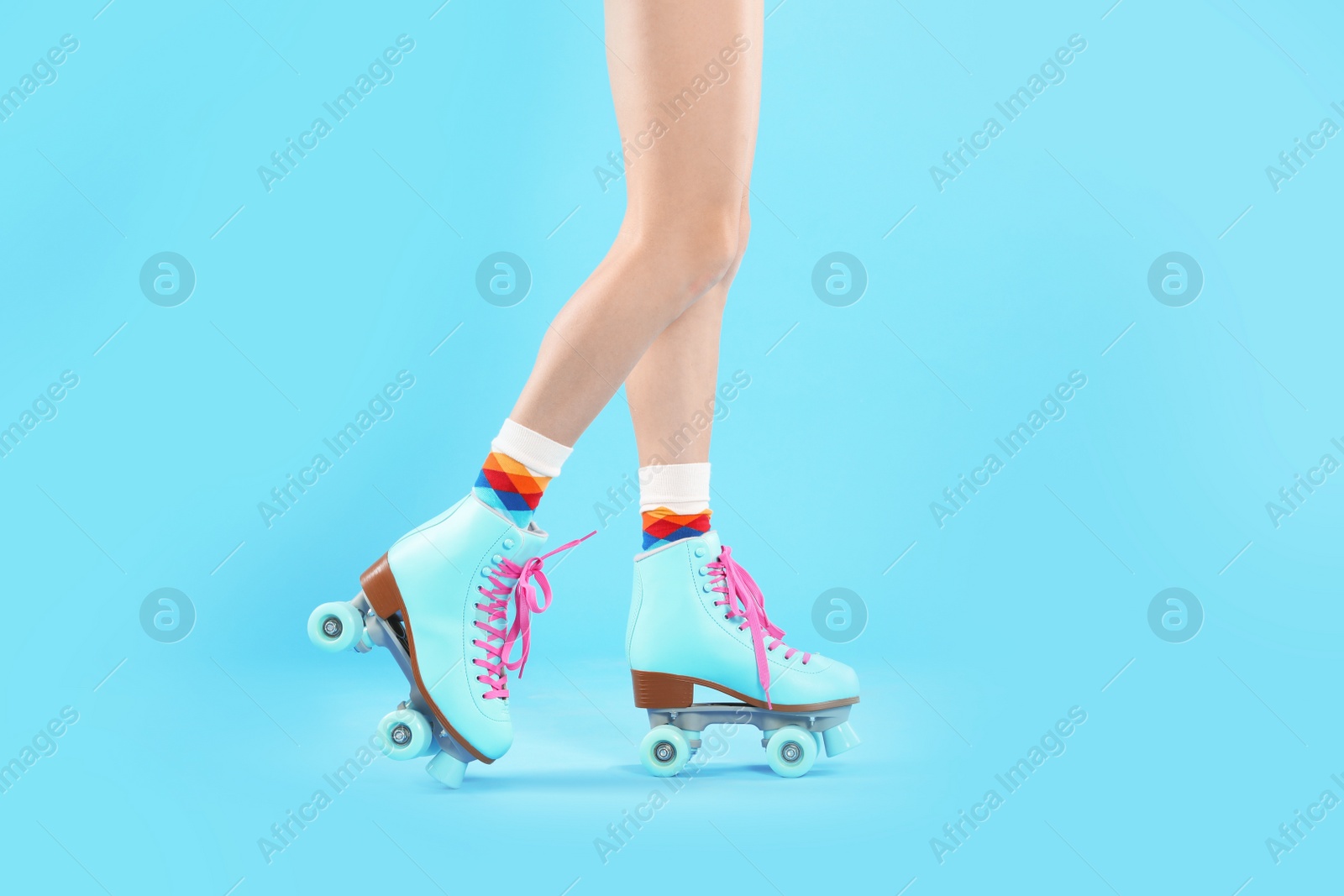 Photo of Young woman with retro roller skates on color background, closeup