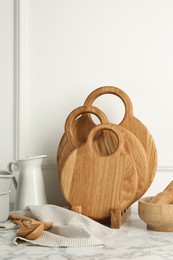 Photo of Wooden cutting boards, spoons and dishware on white marble table