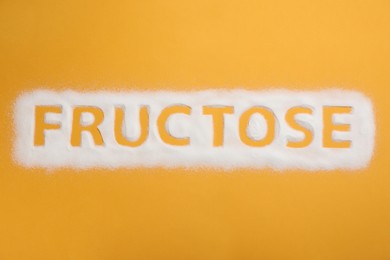 Word Fructose made of sugar on orange background, top view