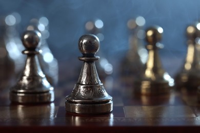 Photo of Metal pawns on chess board, selective focus. Space for text