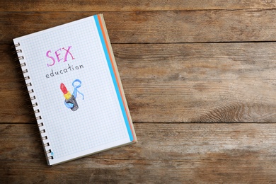 Photo of Notebook with phrase "SEX EDUCATION" on wooden background, top view. Space for text