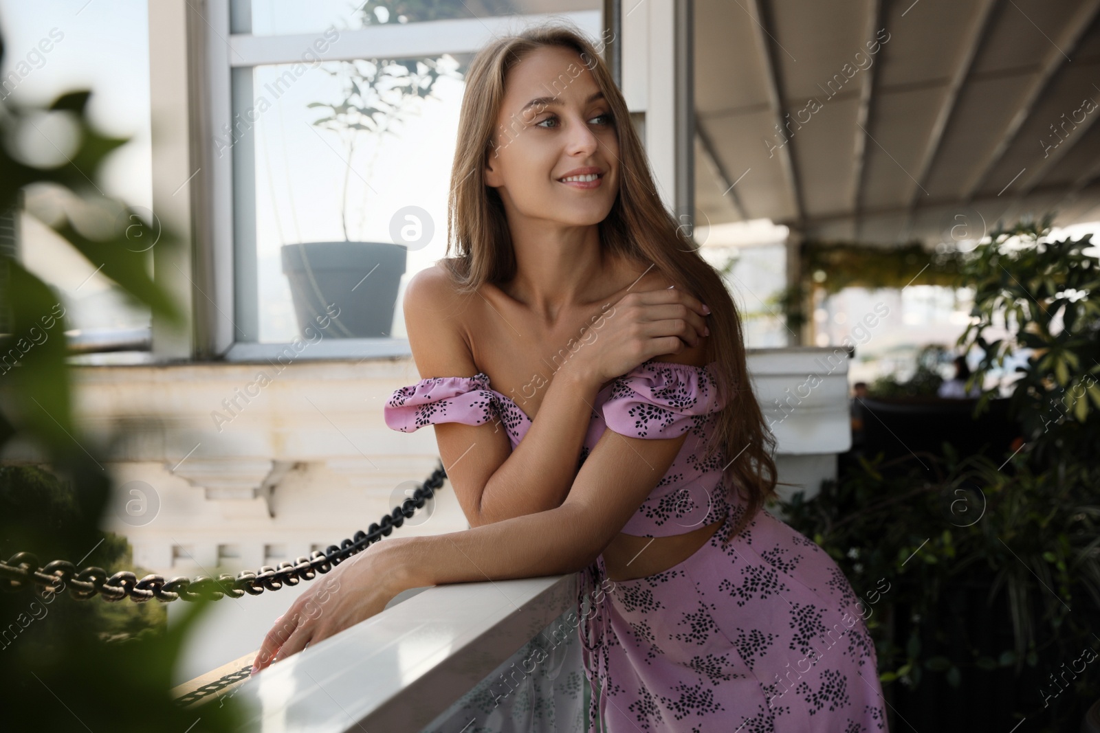 Photo of Beautiful young woman with long hair standing on balcony