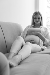 Photo of Beautiful pregnant woman resting on sofa at home, black and white effect