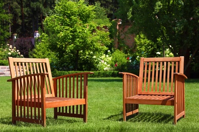 Photo of Wooden armchairs in beautiful garden on sunny day