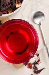 Photo of Cup of fresh hibiscus tea and dry flower leaves on wooden table, flat lay