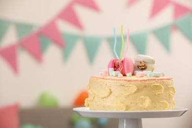 Delicious cake decorated with macarons and marshmallows against blurred background, space for text