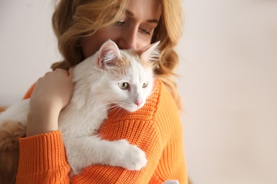Photo of Woman with cute fluffy cat on beige background, closeup