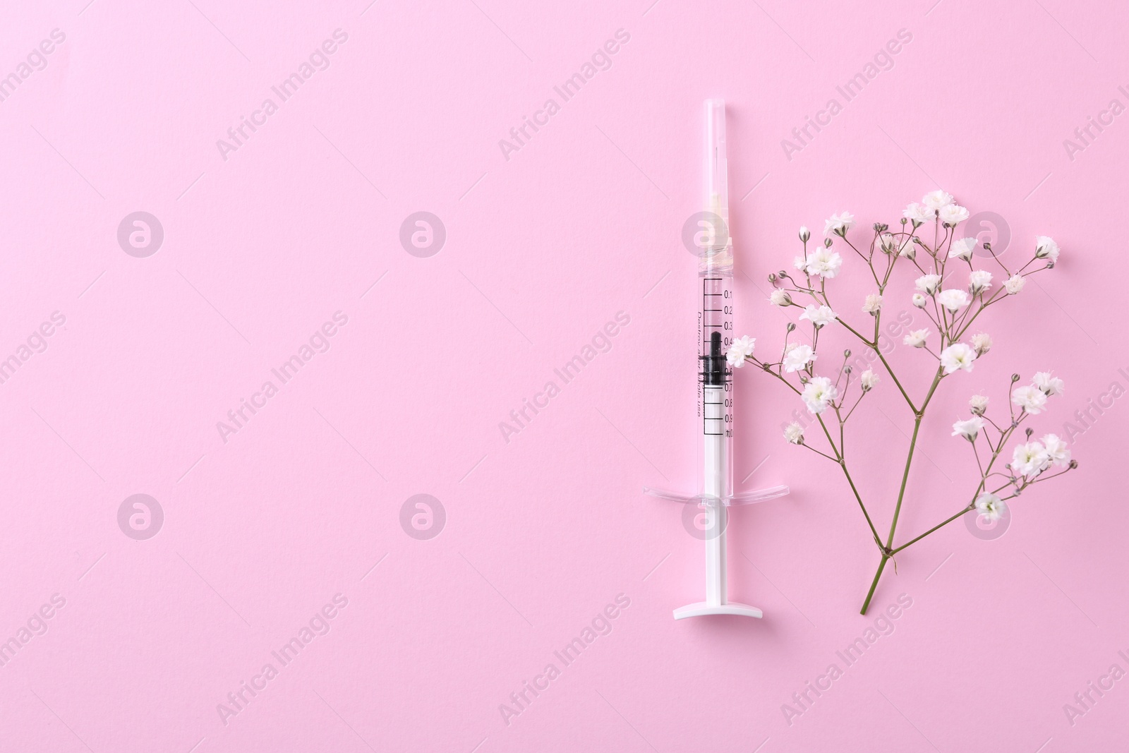 Photo of Cosmetology. Medical syringe and gypsophila on pink background, top view. Space for text