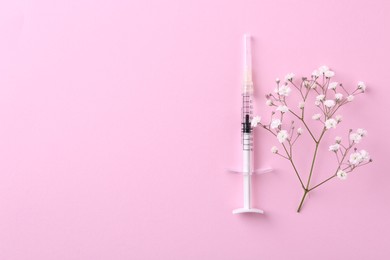 Cosmetology. Medical syringe and gypsophila on pink background, top view. Space for text