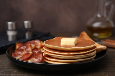 Tasty pancakes served with bacon on wooden table, closeup