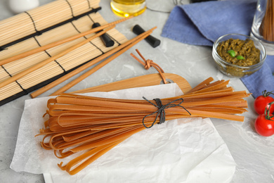 Tied uncooked buckwheat noodles on light grey table