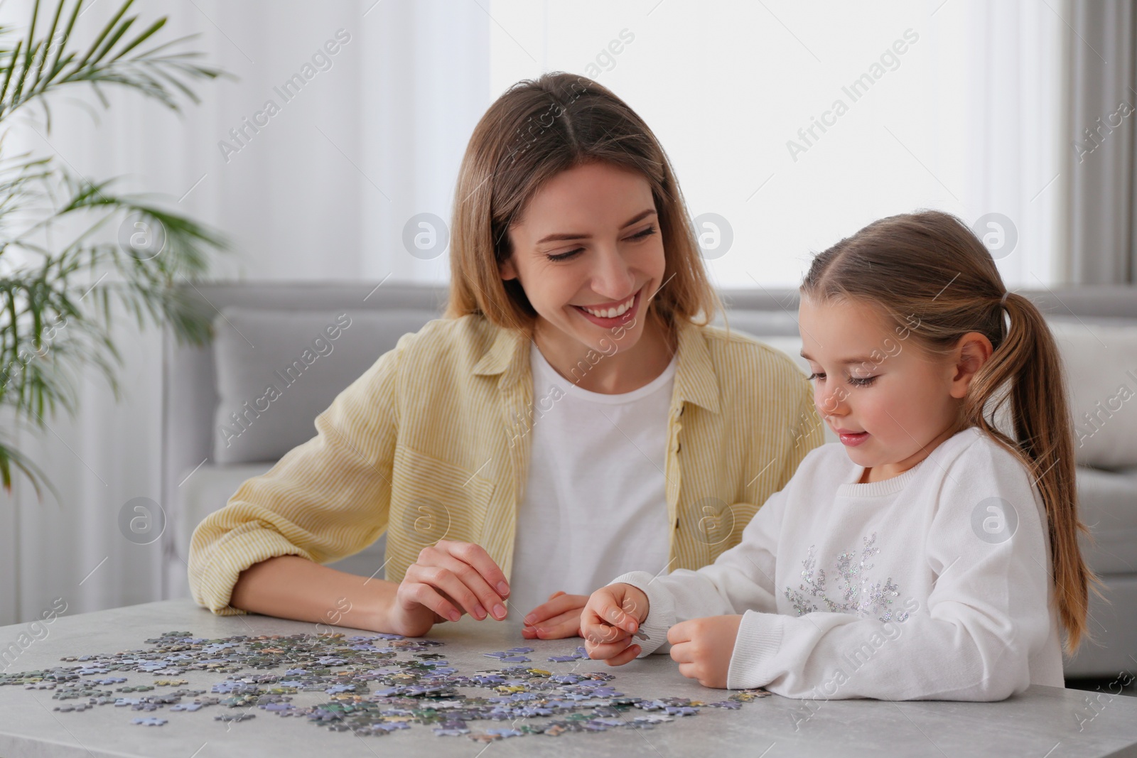 Photo of Woman and his little daughter playing with puzzles at home