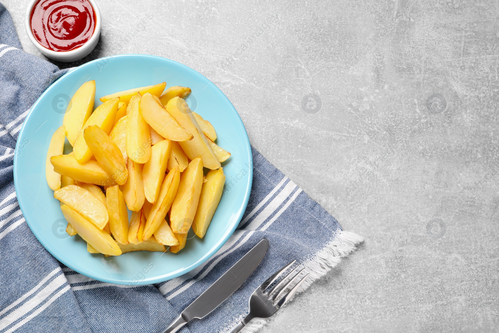 Photo of Plate with tasty baked potato wedges and sauce on grey table, flat lay. Space for text