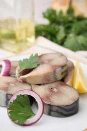 Photo of Slices of tasty salted mackerel with lemon and onion on plate, closeup
