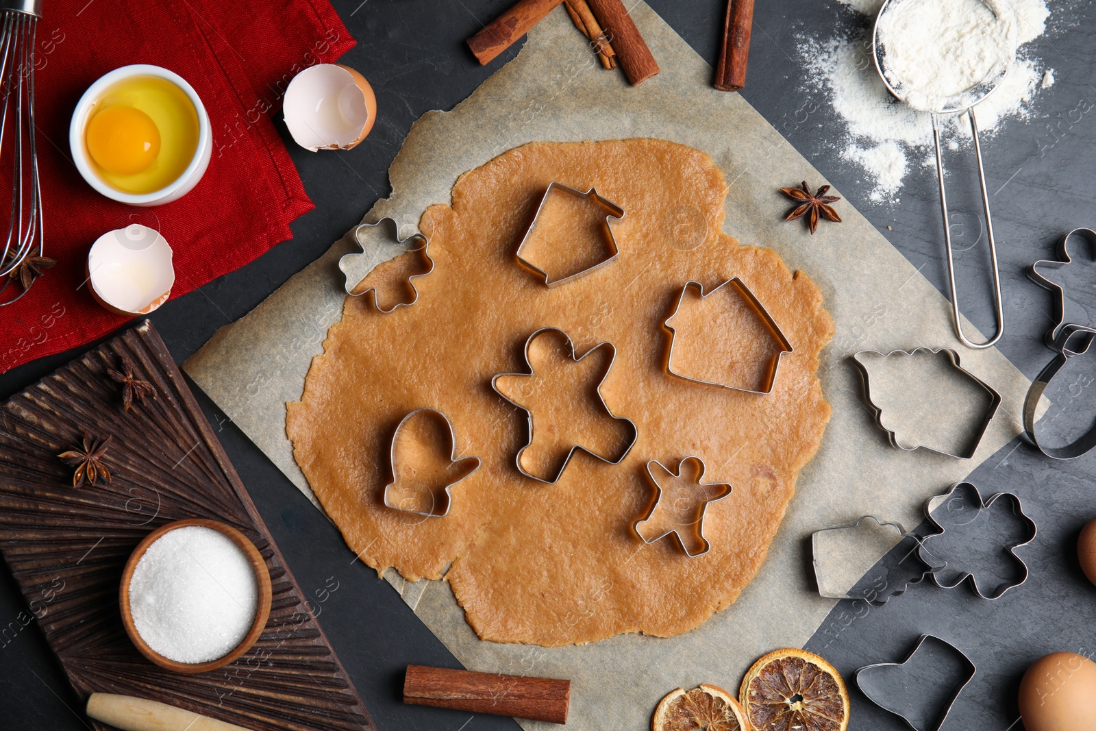 Photo of Raw dough, different cutters and ingredients for Christmas cookies on grey table, flat lay