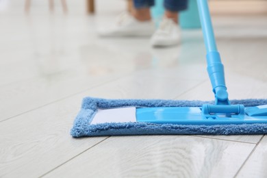 Photo of Washing of parquet floor with mop indoors, closeup