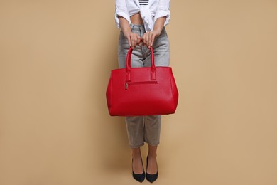 Young woman with stylish bag on beige background, closeup