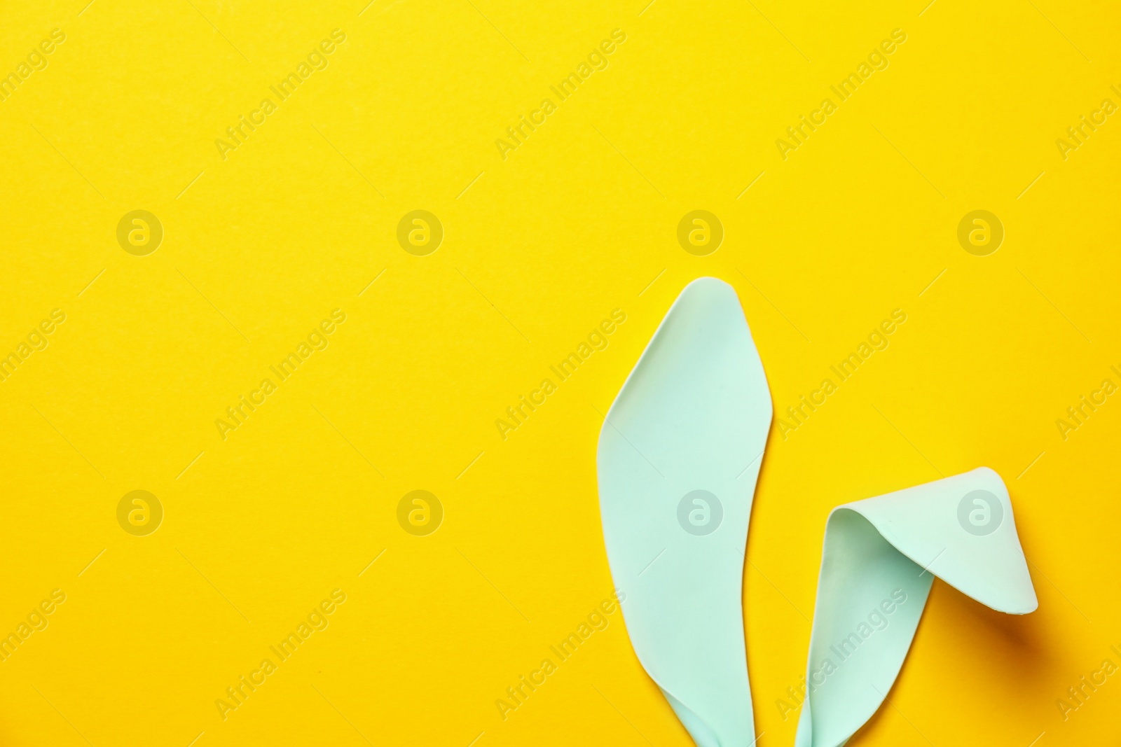 Photo of Funny Easter bunny ears on color background, top view with space for text