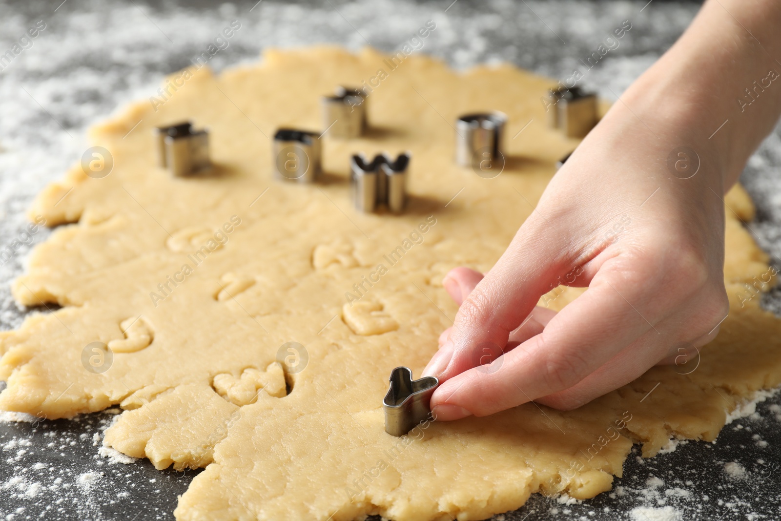 Photo of Shortcrust pastry. Woman making cookies with cutter at grey table, closeup