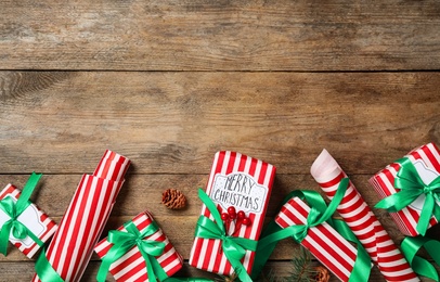 Photo of Christmas gift boxes with green bows on wooden background, flat lay. Space for text