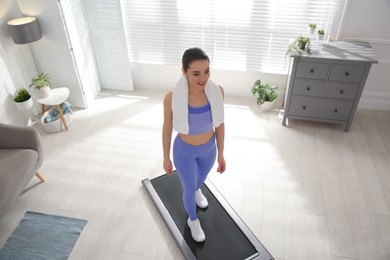 Photo of Sporty woman training on walking treadmill at home, above view