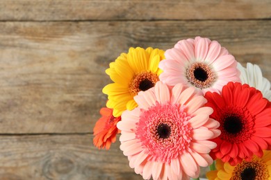 Photo of Bouquet of beautiful colorful gerbera flowers on wooden background. Space for text