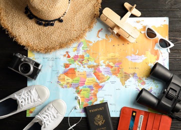 Photo of Flat lay composition with tourist items and world map on wooden background. Travel agency