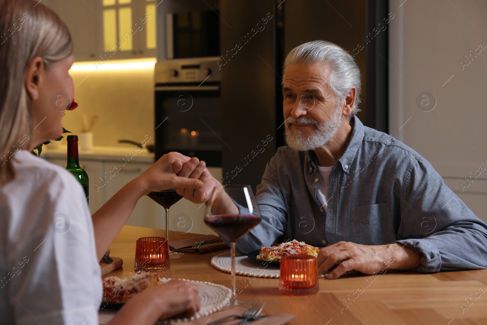 Photo of Affectionate senior couple having romantic dinner at home