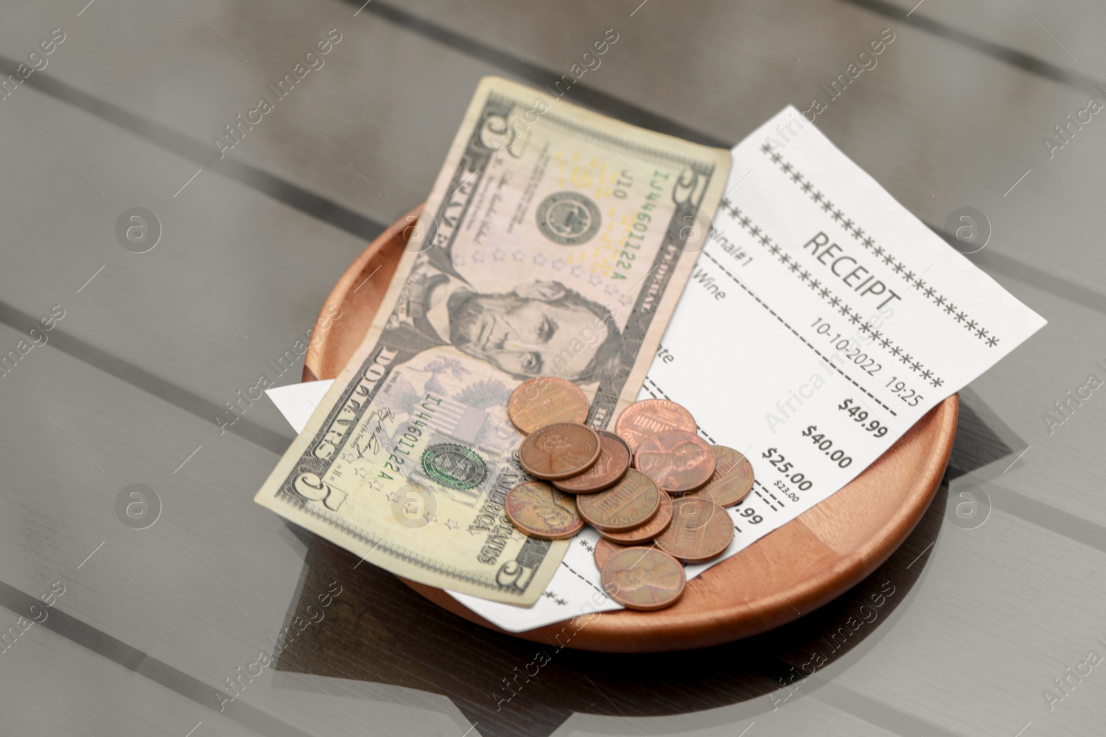 Photo of Tips and receipt on wooden table, closeup