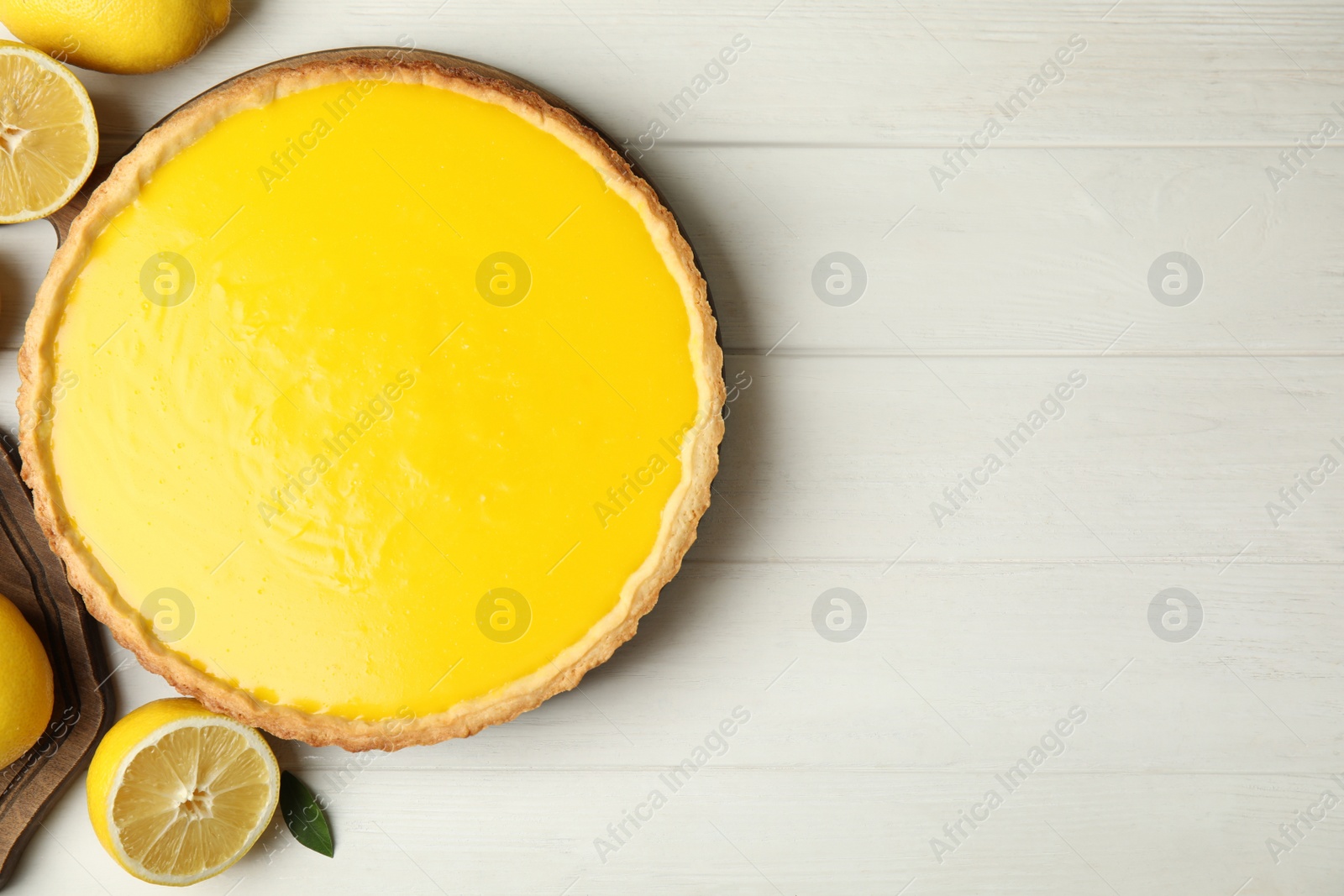 Photo of Delicious homemade lemon pie and fresh fruits on white wooden table, flat lay. Space for text