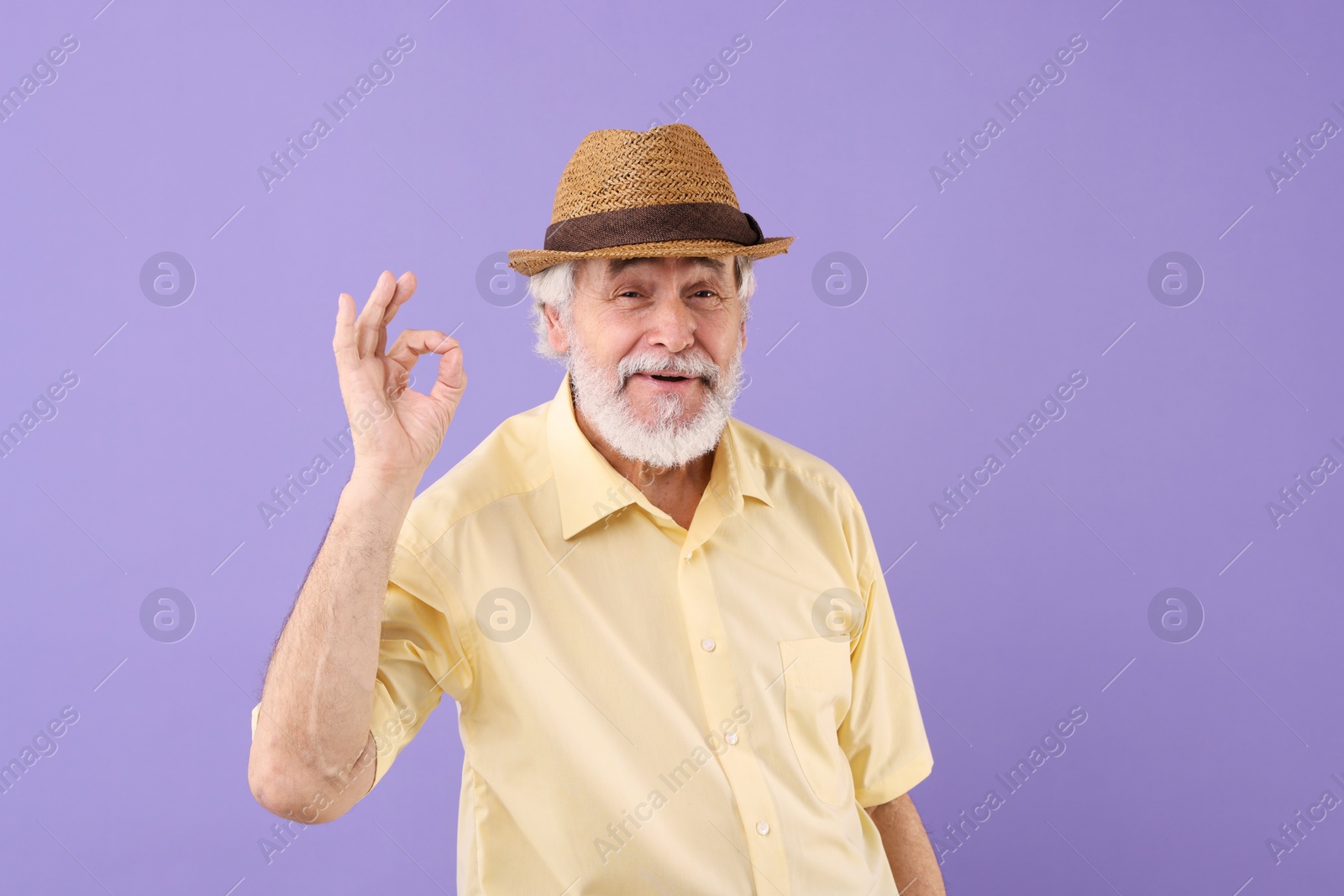 Photo of Portrait of stylish grandpa with hat showing ok gesture on purple background