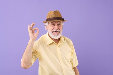 Photo of Portrait of stylish grandpa with hat showing ok gesture on purple background