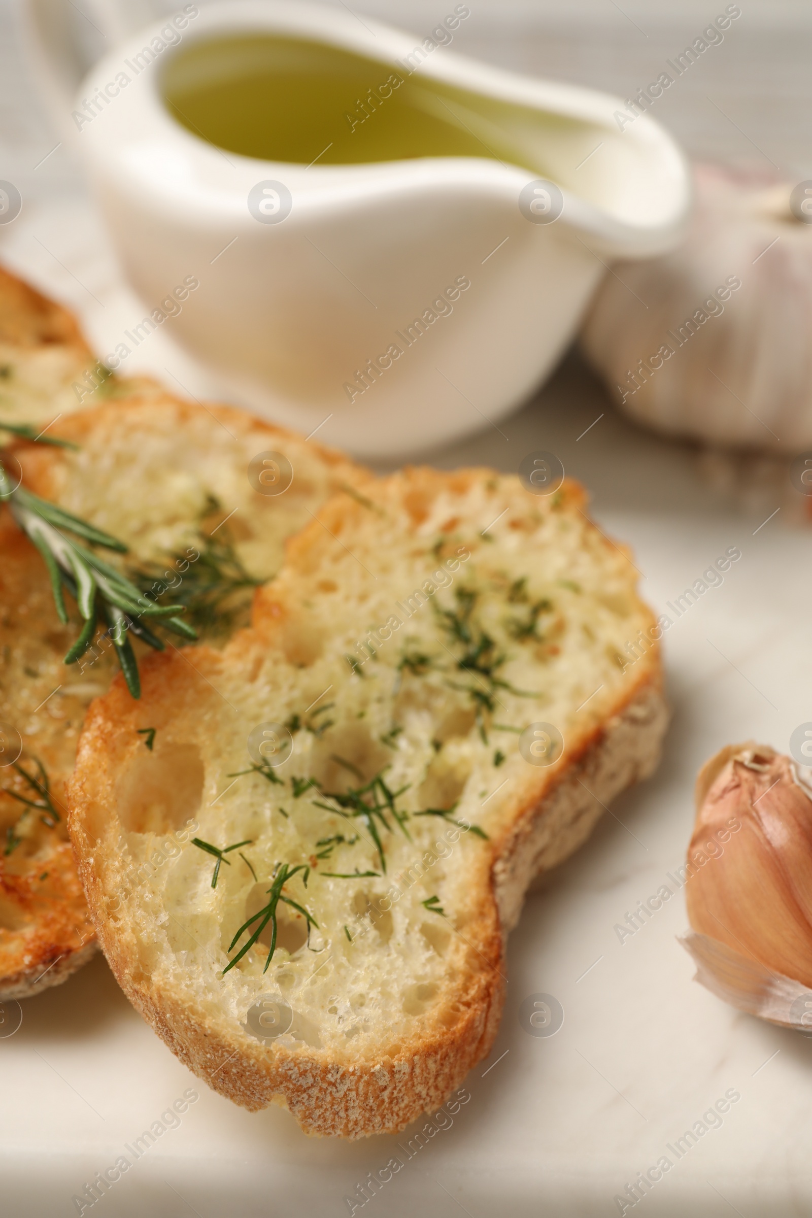 Photo of Tasty baguette with garlic, dill, rosemary and oil on board, closeup