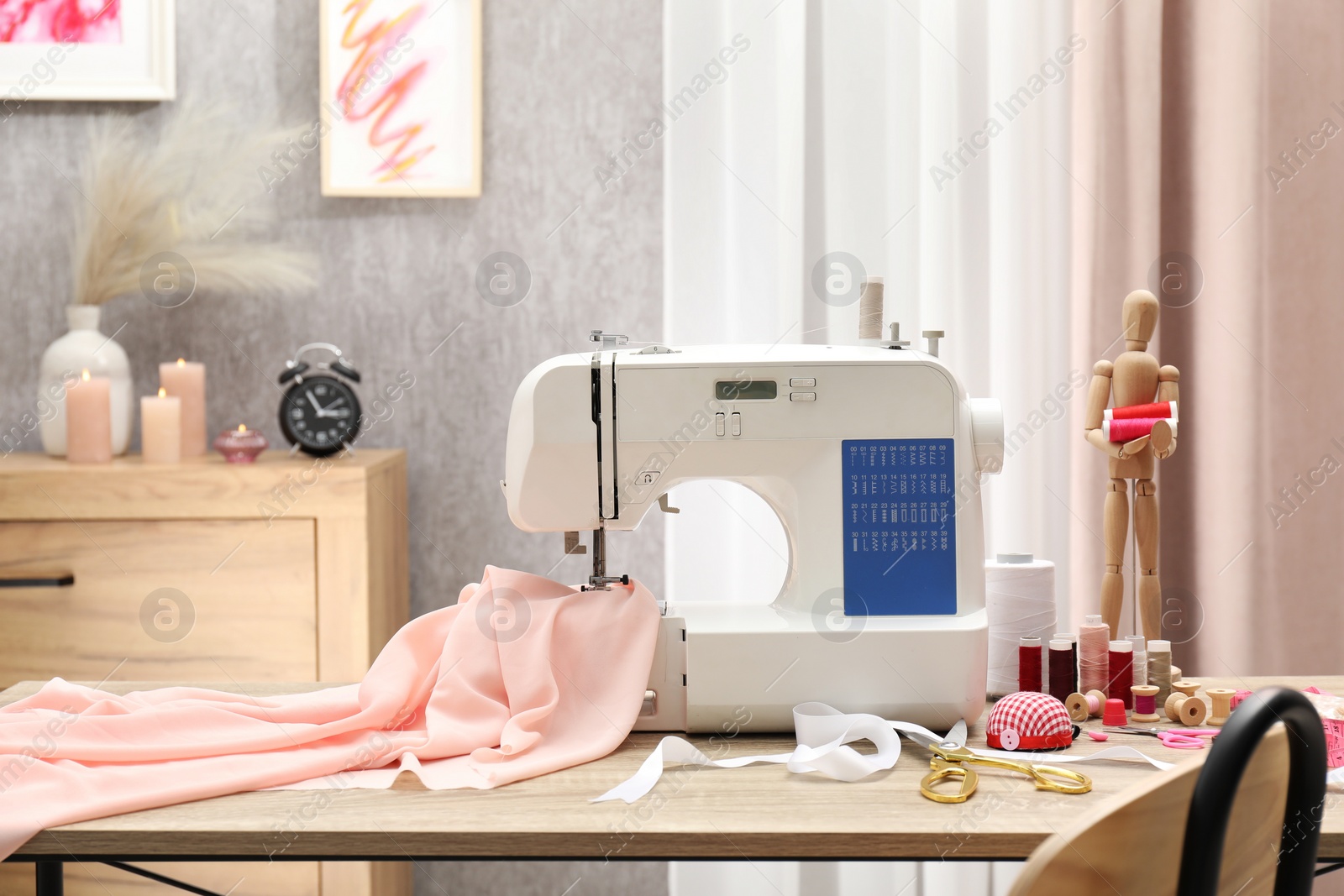 Photo of White sewing machine, cloth, craft accessories and mannequin on wooden table indoors