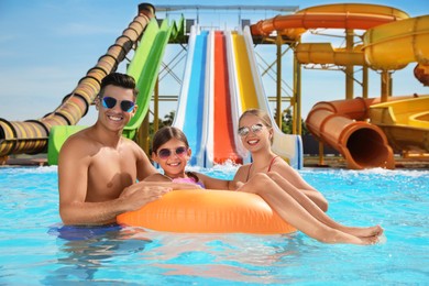 Happy family with inflatable ring in swimming pool at water park