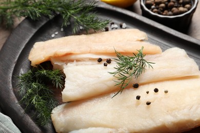 Raw cod fish, dill and spices on table, closeup