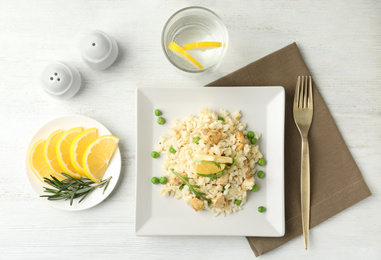 Photo of Delicious chicken risotto served on white wooden table, flat lay