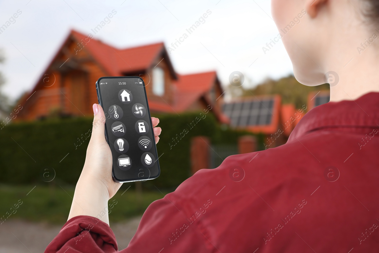 Image of Woman using smart home control system via mobile phone near house outdoors, closeup