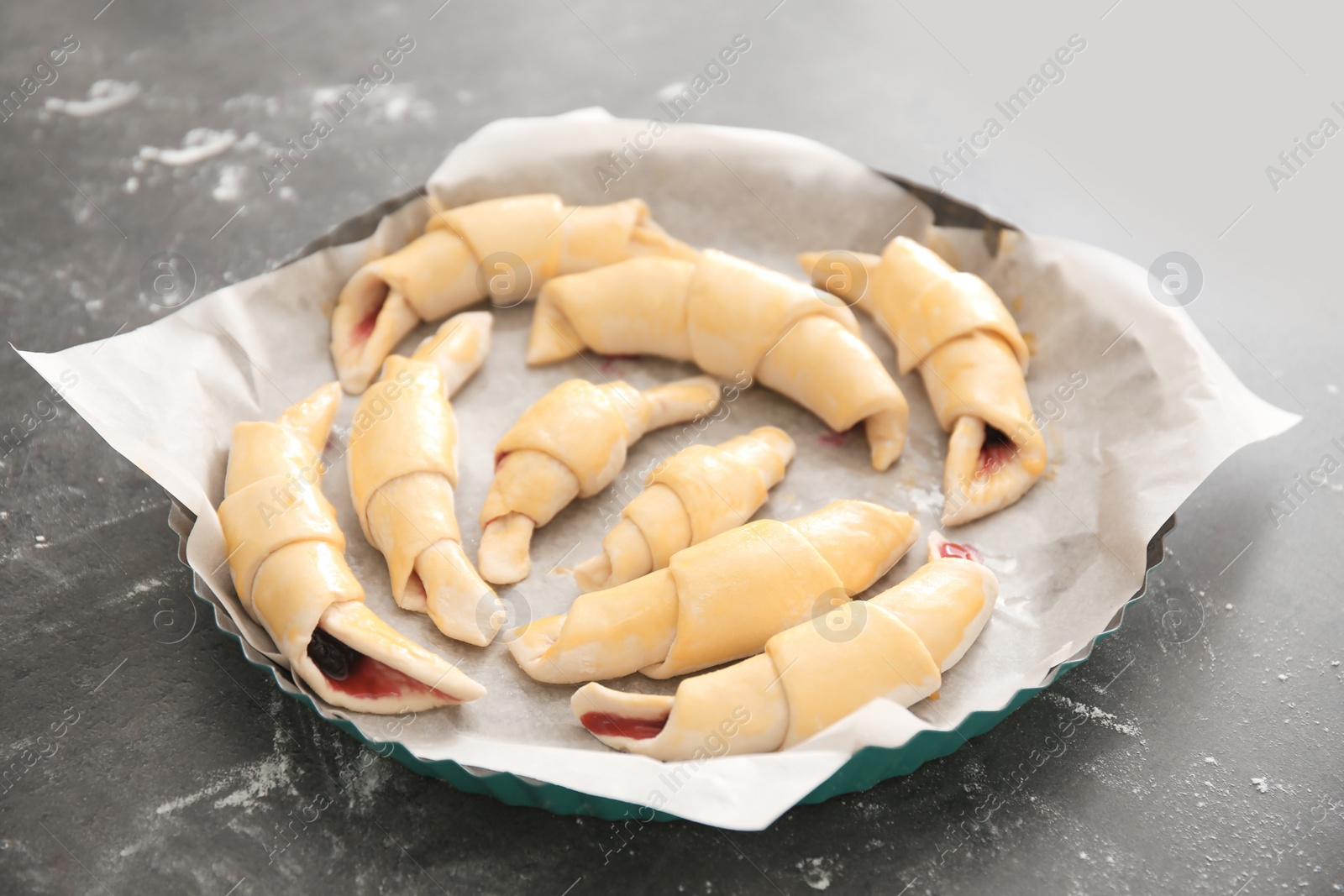 Photo of Baking dish with raw croissants on table