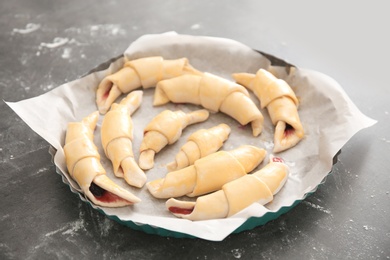 Photo of Baking dish with raw croissants on table
