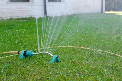 Automatic sprinkler watering green grass on lawn outdoors