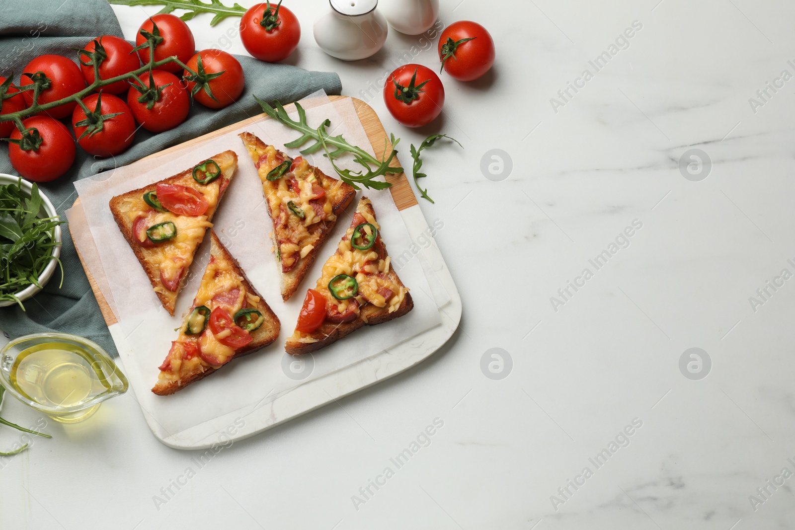 Photo of Tasty pizza toasts and ingredients on white marble table, flat lay. Space for text
