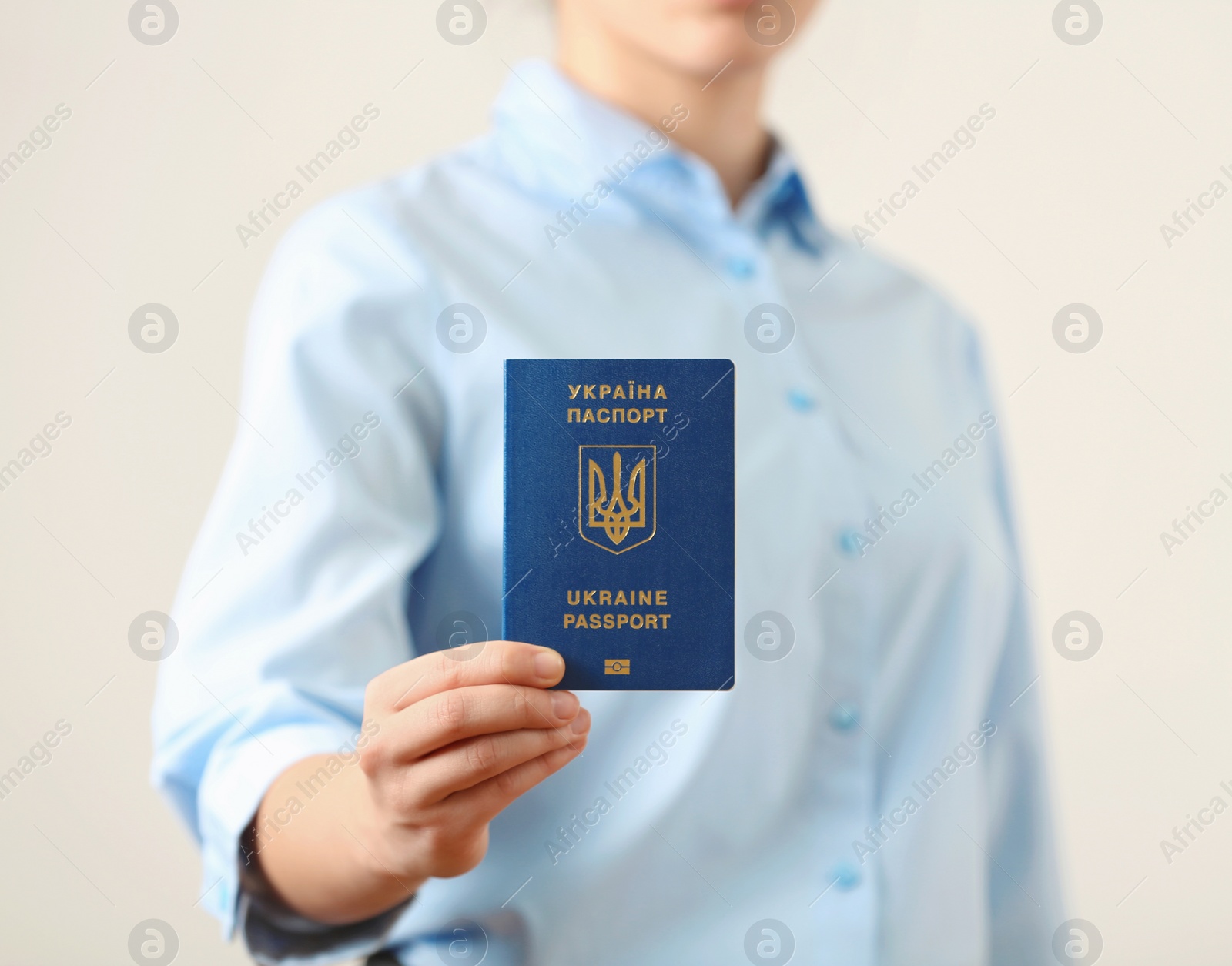 Photo of Woman holding Ukrainian travel passport on light background, closeup. International relationships