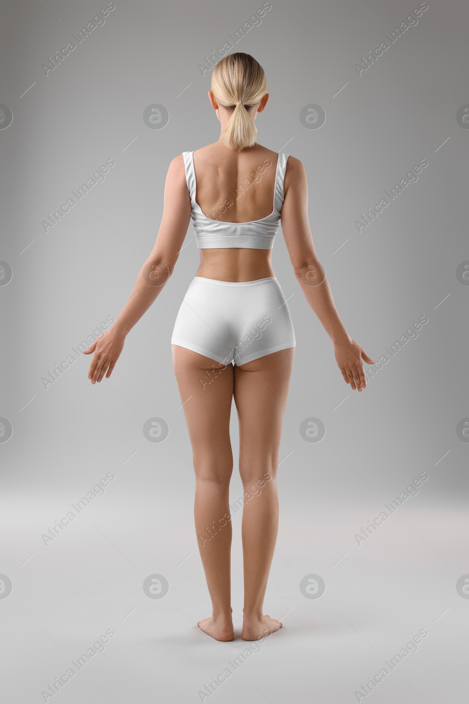 Photo of Sporty woman on grey background, back view