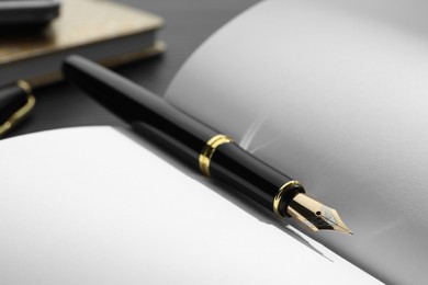Photo of Stylish black fountain pen on open notebook, closeup