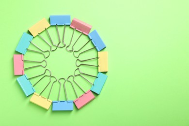 Photo of Colorful binder clips on green background, flat lay. Space for text